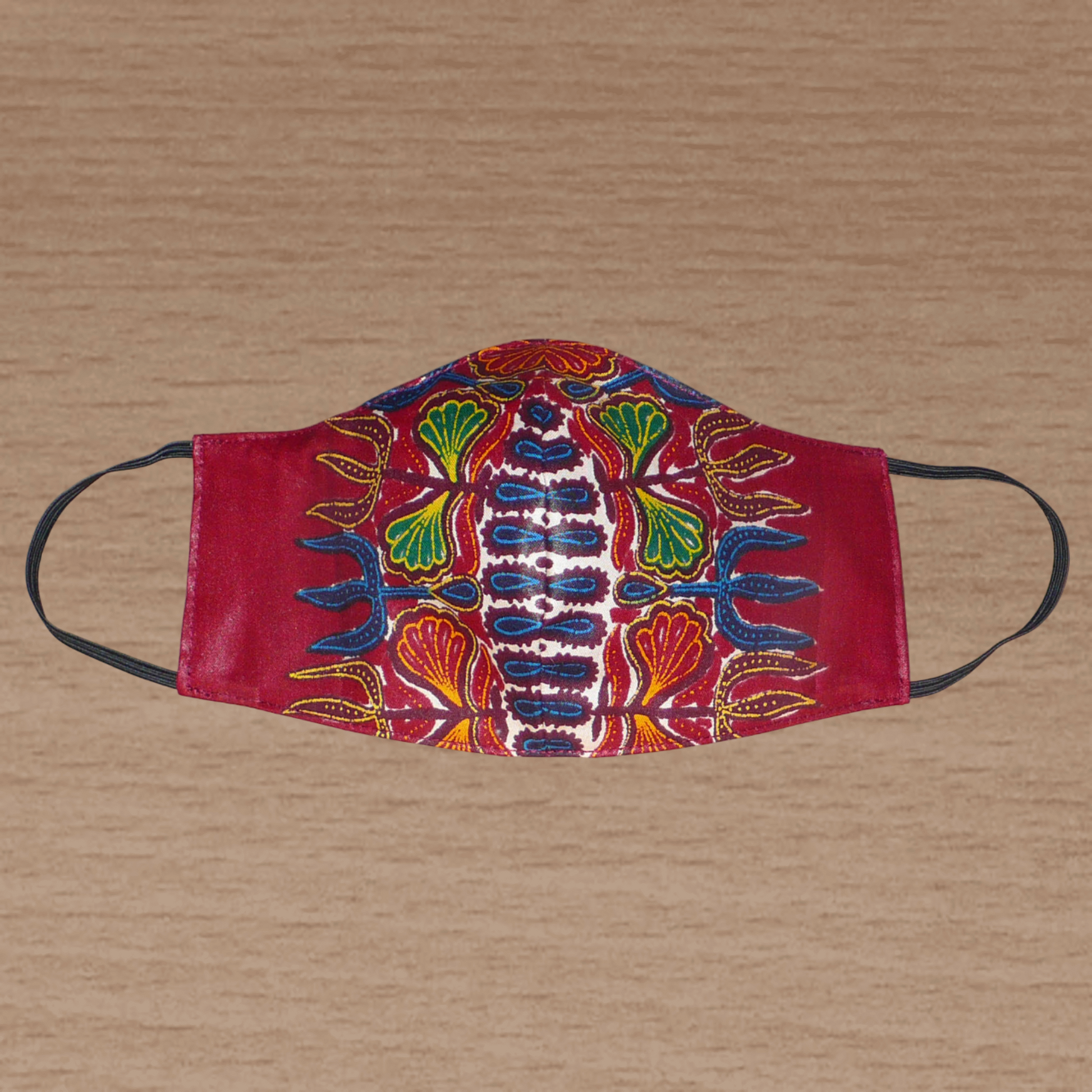 Masque facial en tissu africain bordeaux imprimé de motifs floraux à porter avec des élastiques. En vue d'une utilisation eco-responsable, il est lavable et réutilisable.