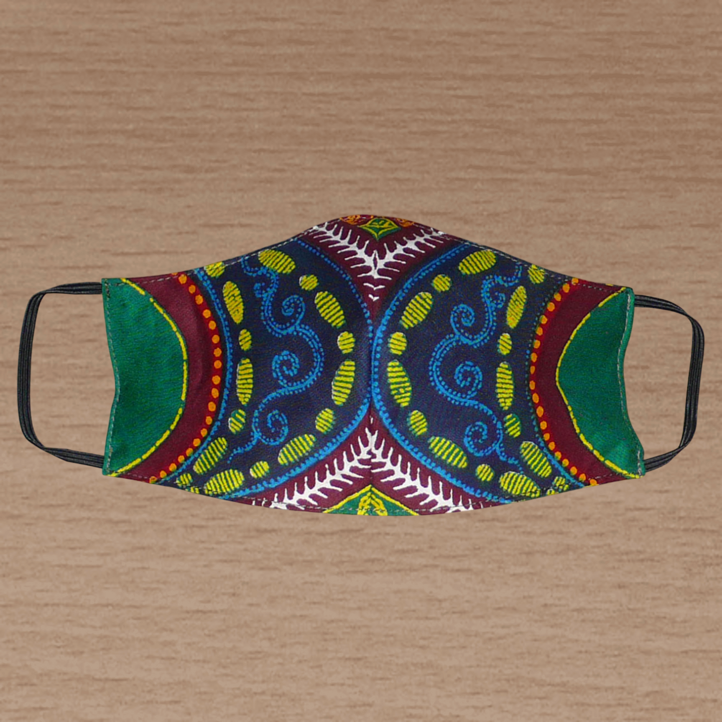 Masque textile pour homme à la coupe ajustée, cousu dans un beau tissu africain en coton à motifs tribaux ; il se porte avec des élastiques. En vue d'une utilisation  éco-responsable, ce masque est lavable et réutilisable.  Ce masque au style afro-caribéen mesure 21 cm de long, et 40 cm en comptant les élastiques ; il a une hauteur de 12 cm (du haut du nez jusqu'au menton) et une largeur sur les côtés de 7 cm.