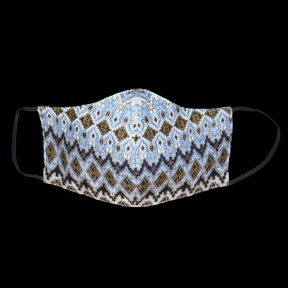 Masque facial textile à la coupe ajustée, cousu dans un tissu en coton bleu ciel à motifs ethniques bleu marine, blancs, marron et dorés ; il se porte avec des élastiques.