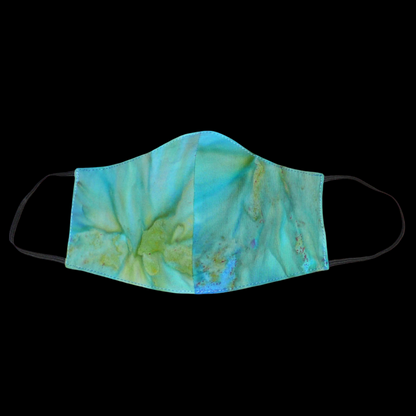 Masque facial textile en coton imprimé Tie and Dye bleu turquoise, avec des nuances de jaune et de vert ; à porter avec des élastiques.