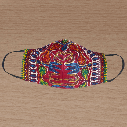 Masque textile facial en tissu africain de couleur bordeaux imprimé de motifs ethniques et floraux multicolores. Lavable et réutilisable, il se porte avec des élastiques.