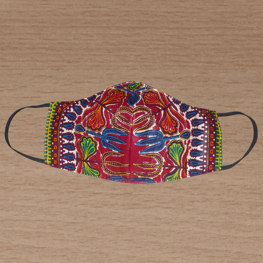 Masque textile facial en tissu africain de couleur bordeaux imprimé de motifs ethniques et floraux multicolores. Lavable et réutilisable, il se porte avec des élastiques.