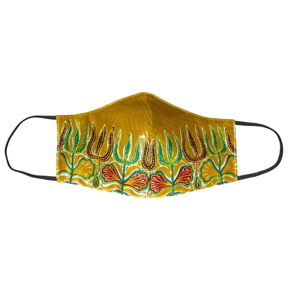 Masque facial en tissu africain en coton de couleur jaune moutarde imprimé de motifs ethniques floraux multicolores ; il se porte avec des élastiques. Fabriqué dans une démarche eco-responsable, ce masque est lavable et réutilisable.