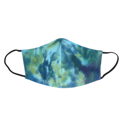 Masque facial coupé et cousu dans un tissu en coton imprimé Tie and Dye bleu avec des nuances de jaune et de rose ; il se porte avec des élastiques. Conçu dans l'optique d'une utilisation eco-friendly, ce masque est lavable et réutilisable.