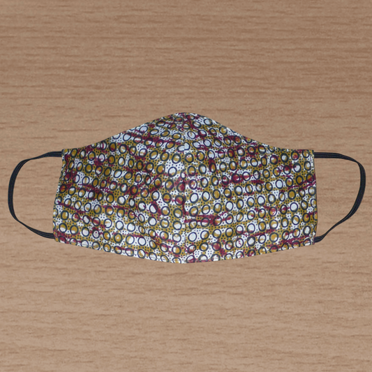 Masque facial textile ajusté coupé dans un tissu africain en coton imprimé de motifs ethniques ; il se porte avec des élastiques. En vue d'une utilisation eco-friendly, ce masque est lavable et réutilisable.  Ce masque à l'allure ethnique chic mesure 21 cm de long, et 40 cm en comptant les élastiques ; il a une hauteur de 12 cm (du haut du nez jusqu'au menton) et une largeur sur les côtés de 7 cm.
