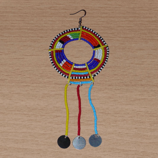 Mono boucle africaine Massai à porter sur une seule oreille : elle se compose de perles de rocaille multicolores enfilées sur des fils de fer montés en cercles fixés sur des charnières en plastique jaune, et se prolonge de franges perlées ornées de disques en métal. Surdimensionnée, elle mesure 15.5 cm de long et 6.5 cm de large, et se porte avec un crochet en acier inoxydable sur une oreille percée.