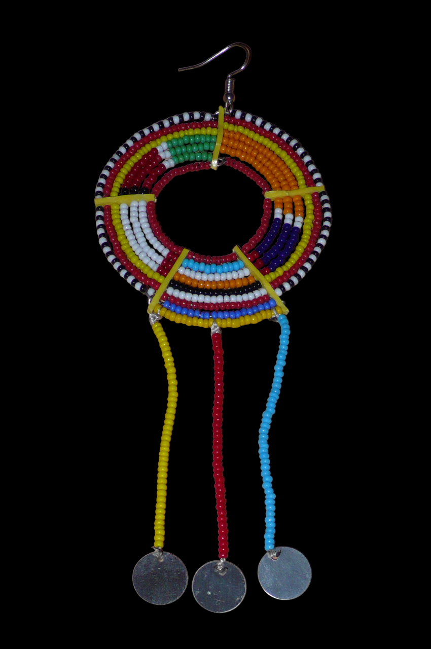 Longue mono boucle d'oreille africaine Massai à porter sur une seule oreille pour un effet visuel asymétrique. Elle se compose de perles de rocaille multicolores enfilées sur des fils de fer montés en cercles fixés sur des charnières en plastique recyclé jaune, et se prolonge de franges perlées ornées de disques en métal. Surdimensionnée, cette mono boucle d'oreille mesure 15.5 cm de long et se porte sur une oreille percée.