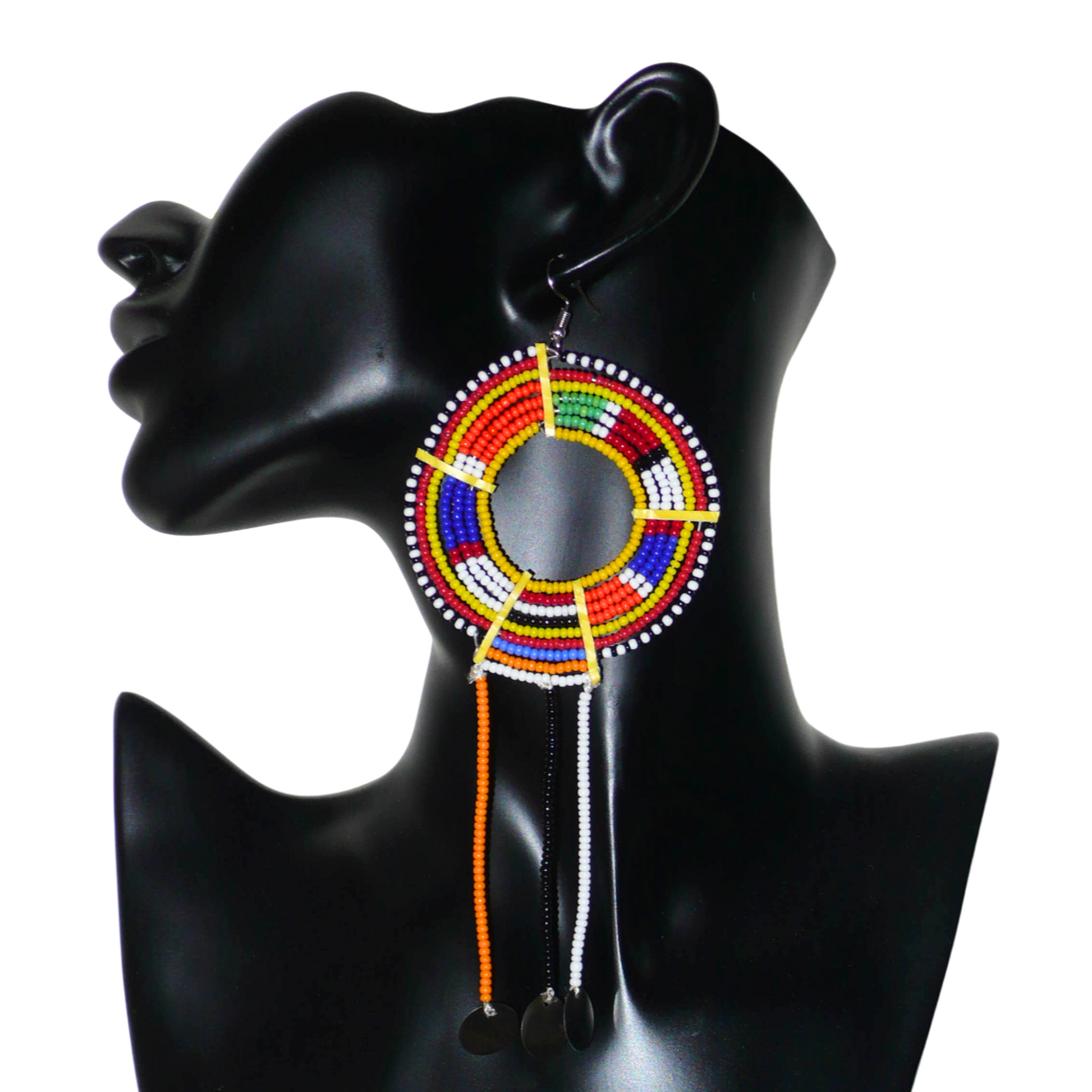 Mono boucle d'oreille confectionnée dans la plus pure tradition tribale Massai, à porter sur une seule oreille pour un effet visuel asymétrique, composée de perles de rocaille jaunes et multicolores enfilées sur des fils de fer montés en cercles et se prolonge de franges perlées ornées de disques métalliques. Surdimensionnée, elle mesure 16 cm de long et se porte sur des oreilles percées.