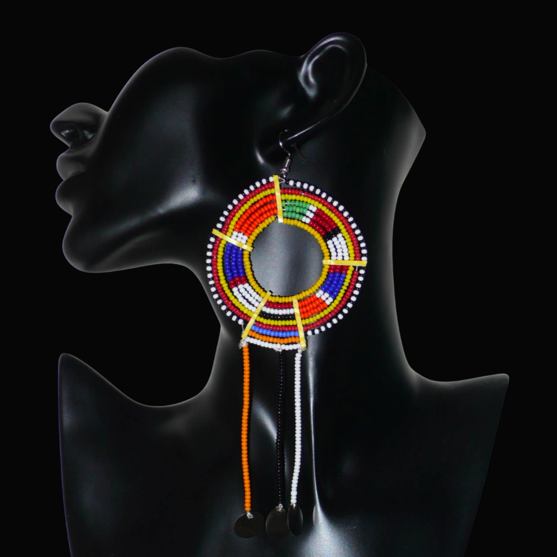 Mono boucle d'oreille confectionnée dans la plus pure tradition tribale Massai, à porter sur une seule oreille pour un effet visuel asymétrique, composée de perles de rocaille jaunes et multicolores enfilées sur des fils de fer montés en cercles et se prolonge de franges perlées ornées de disques métalliques. Surdimensionnée, elle mesure 16 cm de long et se porte sur des oreilles percées.