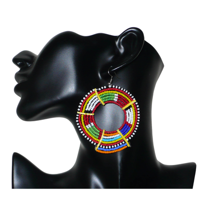 Apportez de l'éclat à votre look avec cette mono boucle africaine Massai à porter d'un seul côté pour un effet visuel asymétrique ! De fabrication traditionnelle artisanale, ce bijou exotique unique se compose de perles de rocaille rouges et multicolores glissées sur des fils de fer montés en cercles et fixés sur des charnières en plastique recyclé jaune. Surdimensionnée, elle mesure 8 cm de long, et se porte sur une oreille percée.