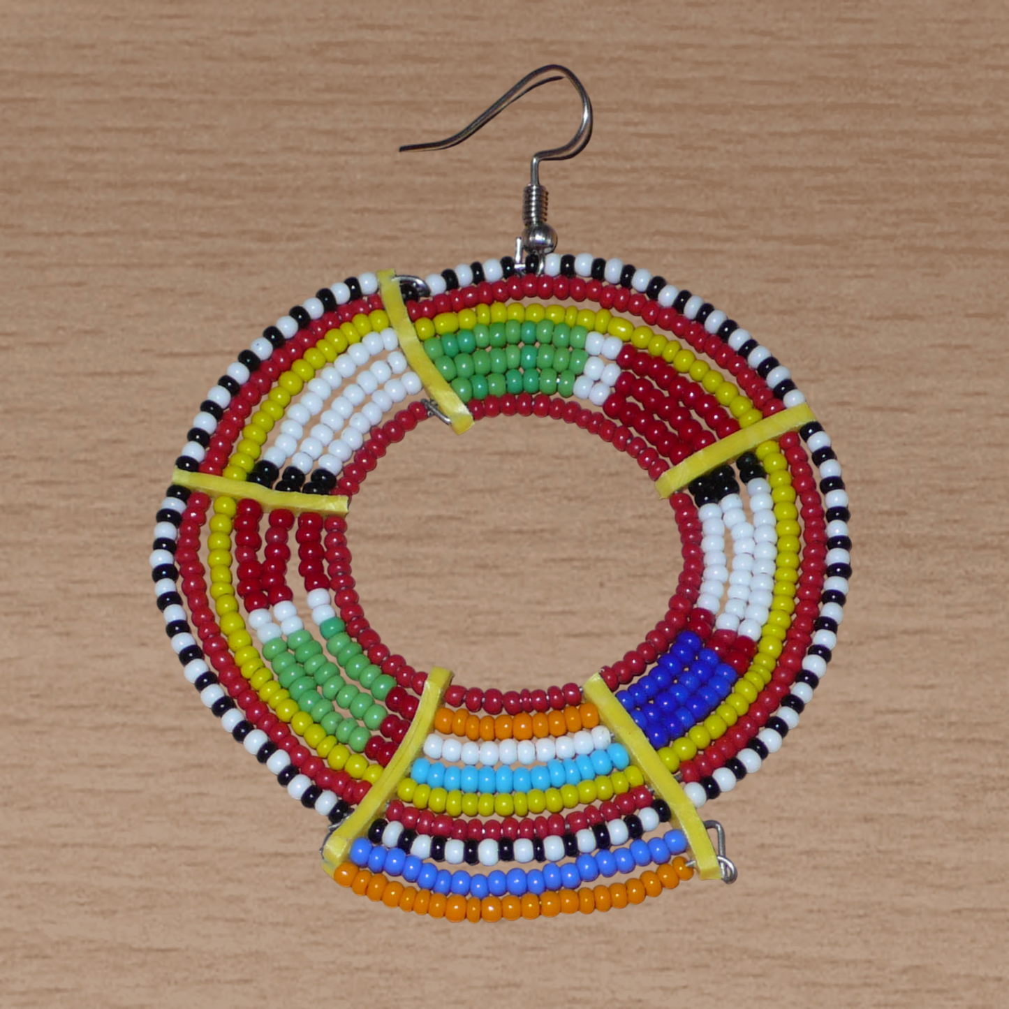Apportez de l'éclat à votre look avec cette mono boucle africaine Massai à porter d'un seul côté pour un effet visuel asymétrique ! De fabrication traditionnelle artisanale, ce bijou exotique unique se compose de perles de rocaille rouges et multicolores glissées sur des fils de fer montés en cercles et fixés sur des charnières en plastique recyclé jaune. Surdimensionnée, elle mesure 8 cm de long, et se porte sur une oreille percée.