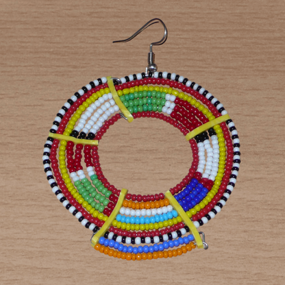 Apportez de l'éclat à votre look avec cette mono boucle africaine Massai à porter d'un seul côté pour un effet visuel asymétrique ! De fabrication traditionnelle artisanale, ce bijou exotique unique se compose de perles de rocaille rouges et multicolores glissées sur des fils de fer montés en cercles et fixés sur des charnières en plastique recyclé jaune. Surdimensionnée, elle mesure 8 cm de long, et se porte sur une oreille percée.