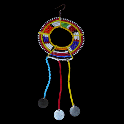 Mono boucle d'oreille à franges fabriquée au Kenya dans la tradition ethnique Massai. À porter sur une seule oreille pour un effet visuel asymétrique, ce bijou se compose de perles de rocaille multicolores glissées sur des fils de fer montés en cercles fixés sur des charnières en plastique recyclé jaune ; il se prolonge de franges perlées ornées de disques en métal. Surdimensionnée, elle mesure 16.5 cm de long et 6.5 cm de large, et se porte sur une oreille percée.