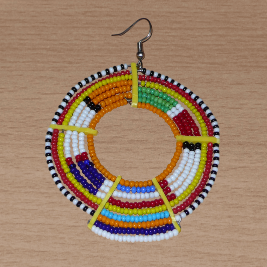 Affirmez votre style et apportez de la couleur à votre look avec cette mono boucle africaine traditionnelle Massai, à porter sur une seule oreille pour un effet visuel asymétrique ! De fabrication artisanale kenyane, ce bijou se compose de perles de rocaille orange et multicolores enfilées sur des fils de fer montés en cercles et fixés sur des charnières en plastique recyclé jaune. Surdimensionnée, cette longue et large mono boucle mesure 8.5 cm de long.