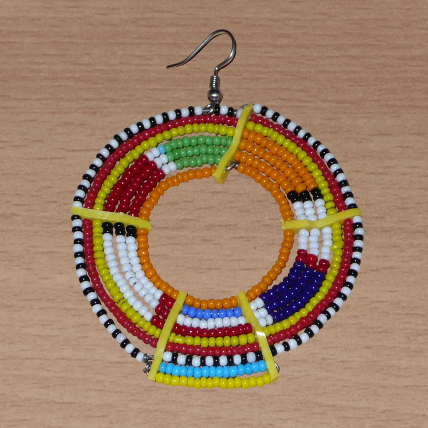 Ajoutez une touche colorée à votre look avec cette mono boucle africaine Massai, à porter d'un seul côté pour un effet visuel asymétrique ! De fabrication kenyane, ce bijou artisanal traditionnel se compose de perles de rocaille orange et multicolores glissées sur des fils de fer montés en cercles et fixés sur des charnières en plastique recyclé jaune. Surdimensionnée, elle mesure 8 cm de long et 6 cm de large, et se porte sur une oreille percée.