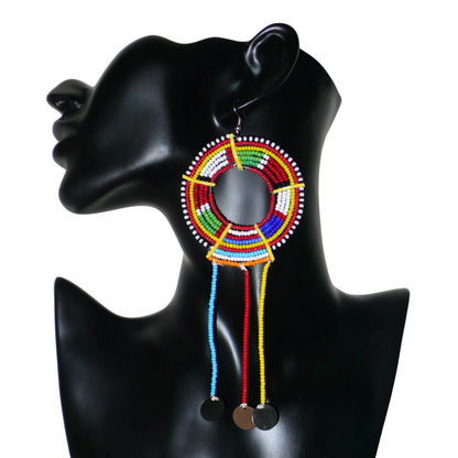 Pièce unique composée de perles de rocaille rouges et multicolores, cette mono boucle d'oreille à franges, confectionnée au Kenya dans la plus pure tradition Massai, est un bijou à porter d'un seul côté, qui apportera à votre look une touche éclatante d'asymétrie visuelle. Surdimensionnée, cette mono boucle au style exotique mesure 16 cm de long et 6 cm de large, et se porte avec un crochet en acier inoxydable sur une oreille percée.