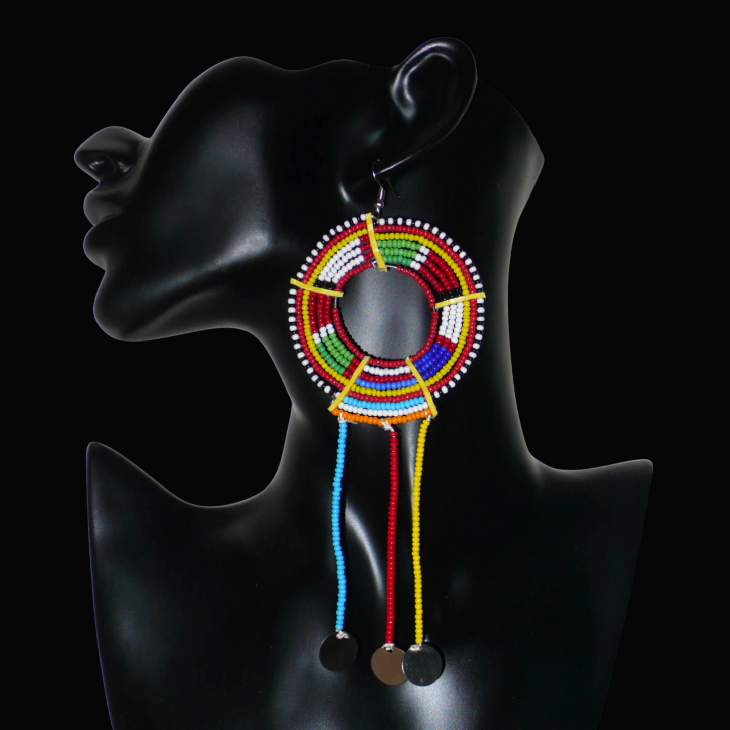 Pièce unique composée de perles de rocaille rouges et multicolores, cette mono boucle d'oreille à franges, confectionnée au Kenya dans la plus pure tradition Massai, est un bijou à porter d'un seul côté, qui apportera à votre look une touche éclatante d'asymétrie visuelle. Surdimensionnée, cette mono boucle au style exotique mesure 16 cm de long et 6 cm de large, et se porte avec un crochet en acier inoxydable sur une oreille percée.