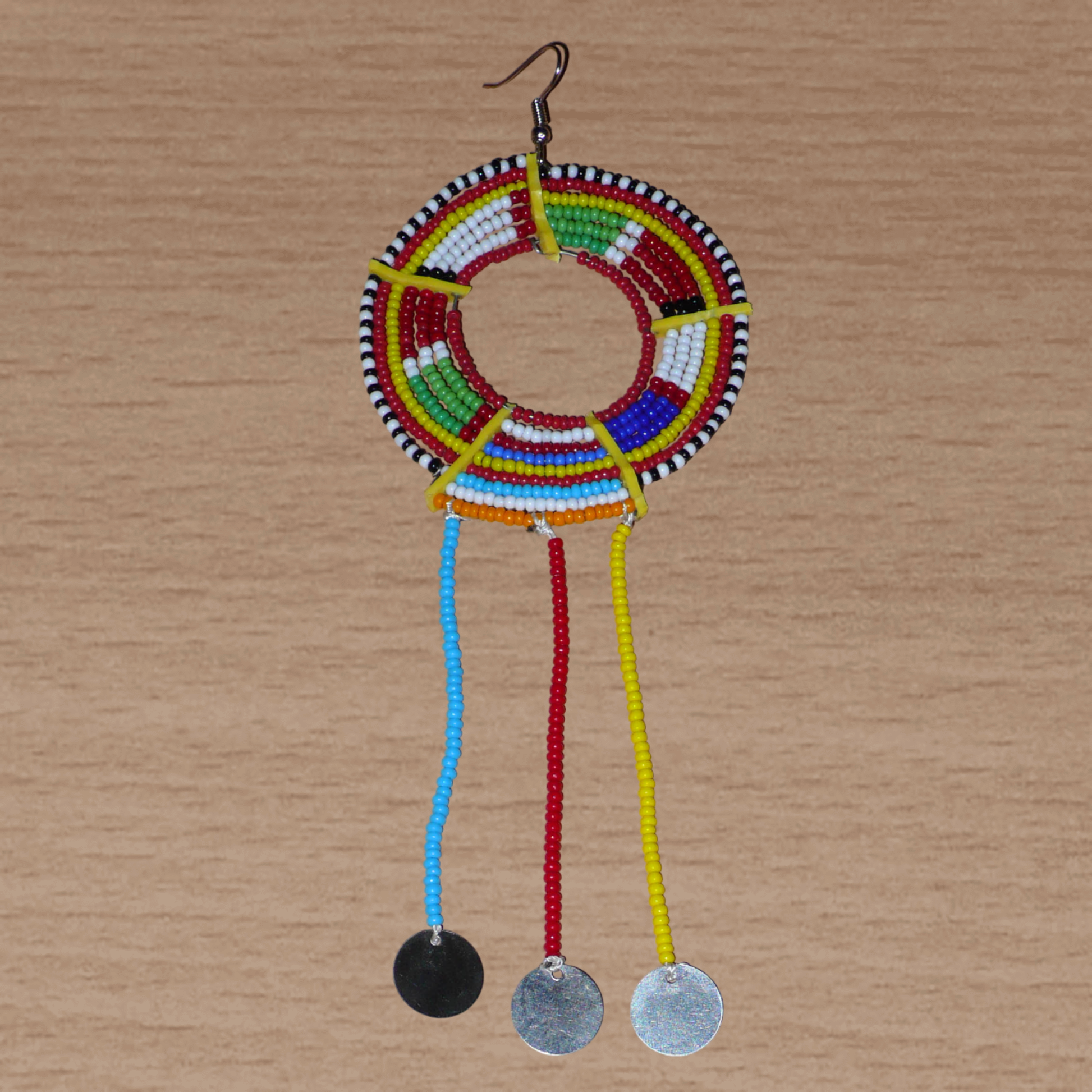 Pièce unique composée de perles de rocaille rouges et multicolores, cette mono boucle d'oreille à franges, confectionnée au Kenya dans la plus pure tradition Massai, est un bijou à porter d'un seul côté, qui apportera à votre look une touche éclatante d'asymétrie visuelle. Surdimensionnée, cette mono boucle au style exotique mesure 16 cm de long et 6 cm de large, et se porte avec un crochet en acier inoxydable sur une oreille percée.