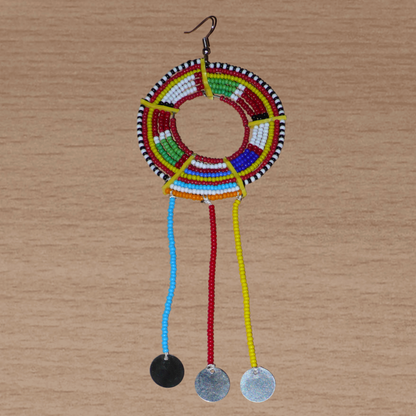 Pièce unique composée de perles de rocaille rouges et multicolores, cette mono boucle d'oreille à franges, confectionnée au Kenya dans la plus pure tradition Massai, est un bijou à porter d'un seul côté, qui apportera à votre look une touche éclatante d'asymétrie visuelle. Surdimensionnée, cette mono boucle au style exotique mesure 16 cm de long et 6 cm de large, et se porte avec un crochet en acier inoxydable sur une oreille percée.