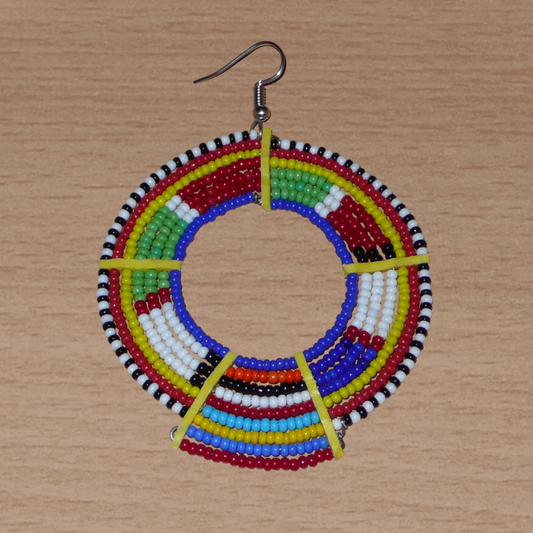 De fabrication traditionnelle kenyane, cette mono boucle ethnique Massai se compose de perles de rocaille bleues et multicolores glissées sur des fils de fer montés en cercles et fixés sur des charnières en plastique recyclé jaune. Surdimensionnée, elles mesure 8.5 cm de long et 6 cm de large, et se porte avec un crochet en acier inoxydable sur une oreille percée.