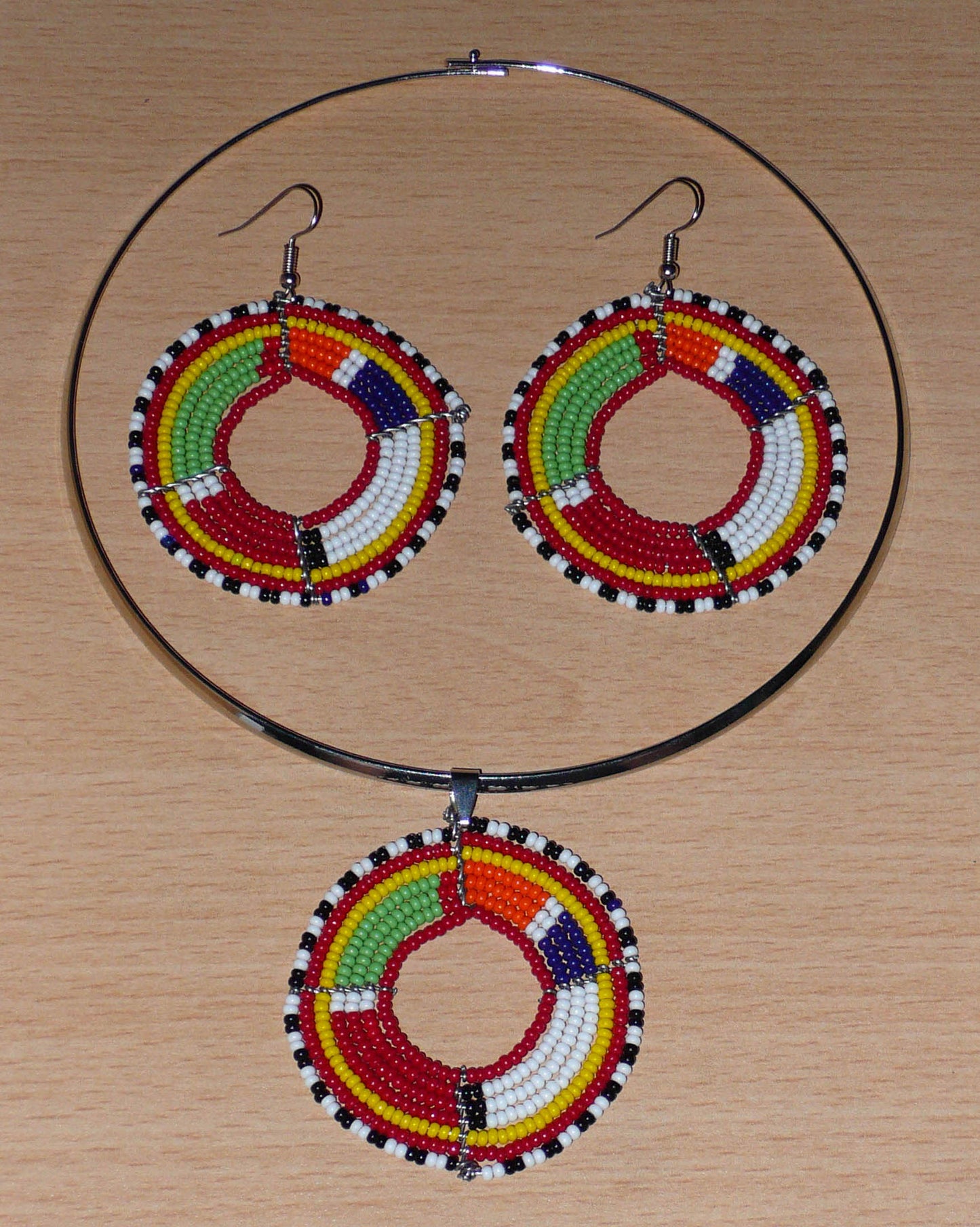 Parure de bijoux ethniques chic composée d'un collier ras-de-cou agrémenté d'un médaillon Massai en perles de rocaille rouges et multicolores, et d'une paire de créoles perlées assorties au collier.