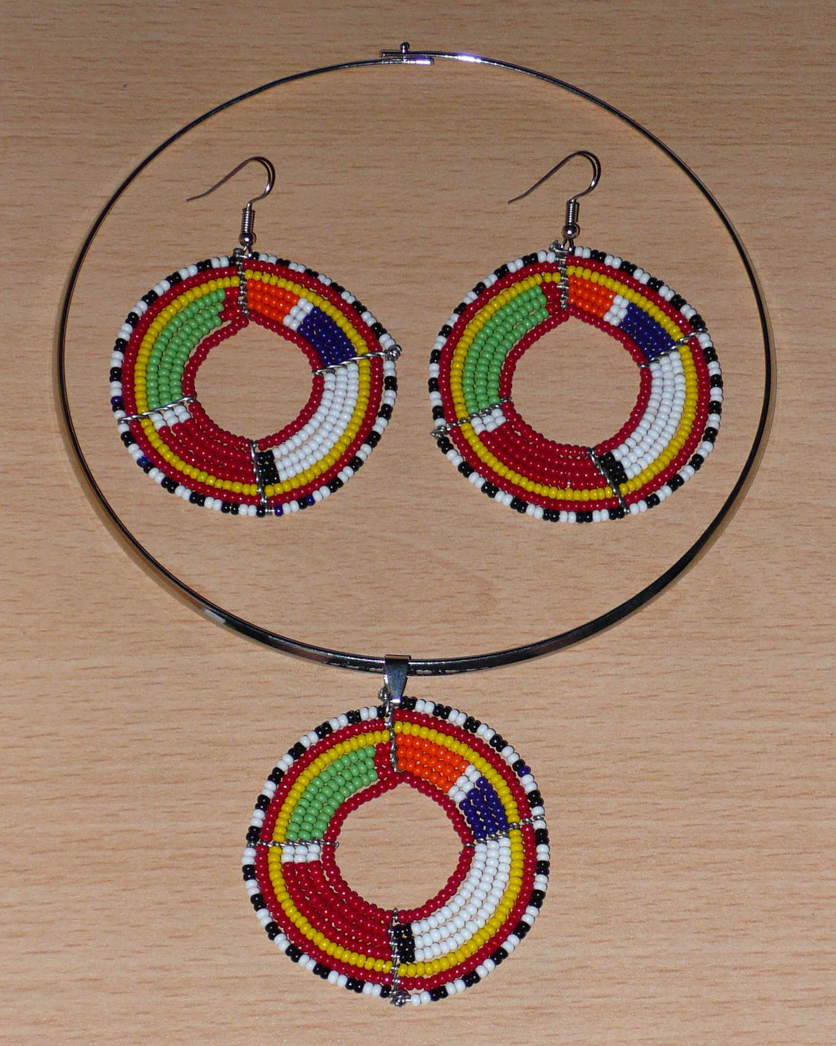 Parure de bijoux ethniques chic composée d'un collier ras-de-cou agrémenté d'un médaillon Massai en perles de rocaille rouges et multicolores, et d'une paire de créoles perlées assorties au collier.