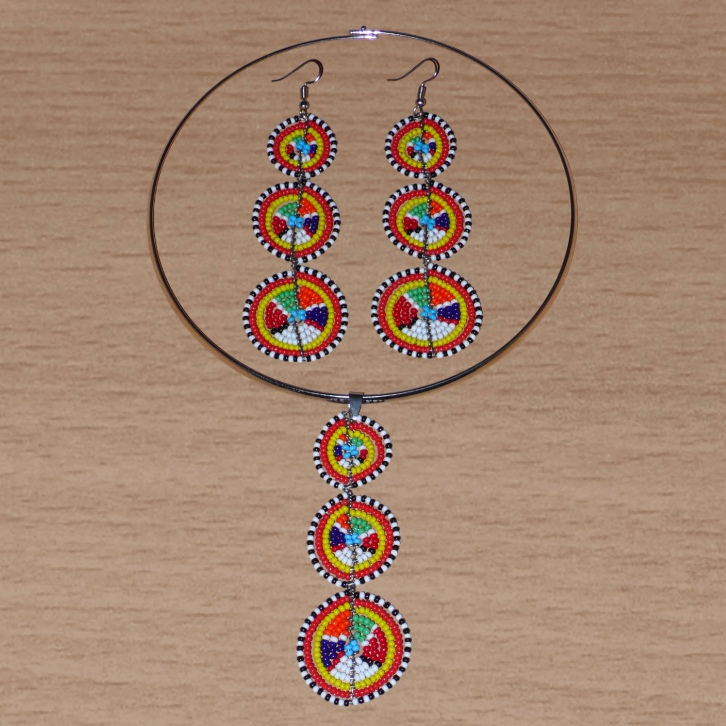 L'esthétique afro chic des années 70 est de mise avec cette parure de bijoux africain Massai ! Elle se compose d'un collier ras de cou en laiton rehaussé d'un long pendentif en perles de rocaille multicolores façonnées en cercles superposés, et d'une paire de boucles d'oreilles assorties.