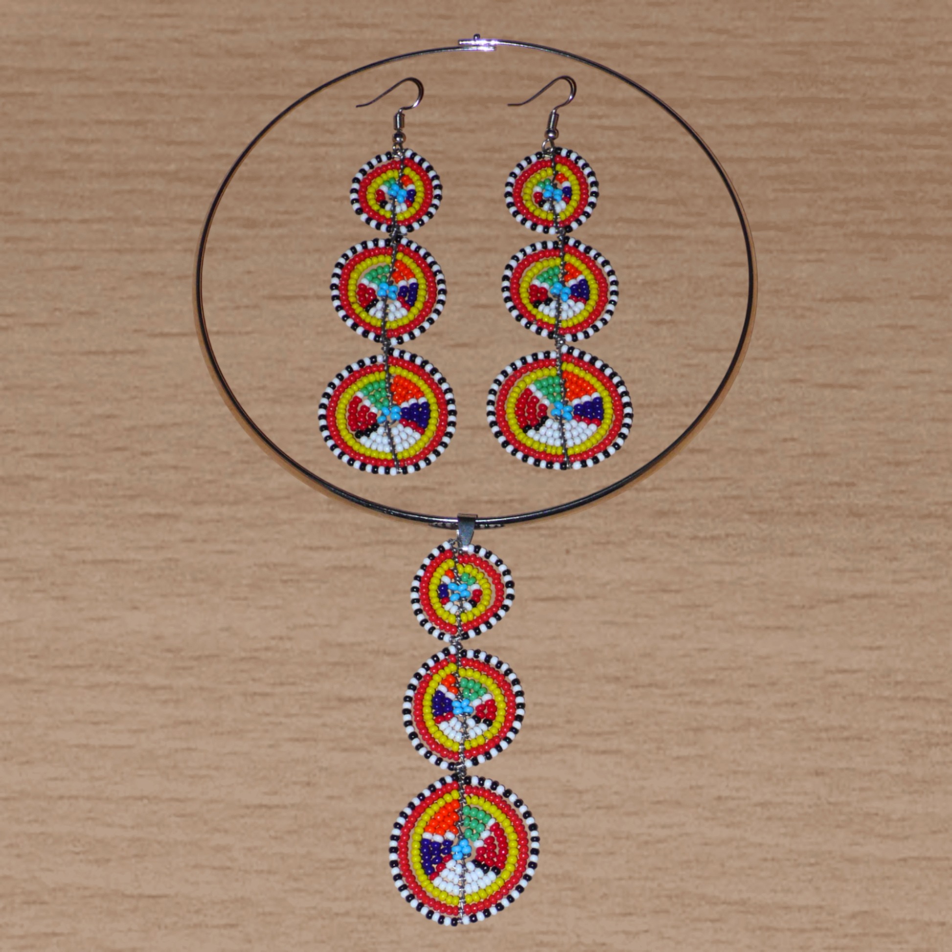 L'esthétique afro chic des années 70 est de mise avec cette parure de bijoux africain Massai ! Elle se compose d'un collier ras de cou en laiton rehaussé d'un long pendentif en perles de rocaille multicolores façonnées en cercles superposés, et d'une paire de boucles d'oreilles assorties.
