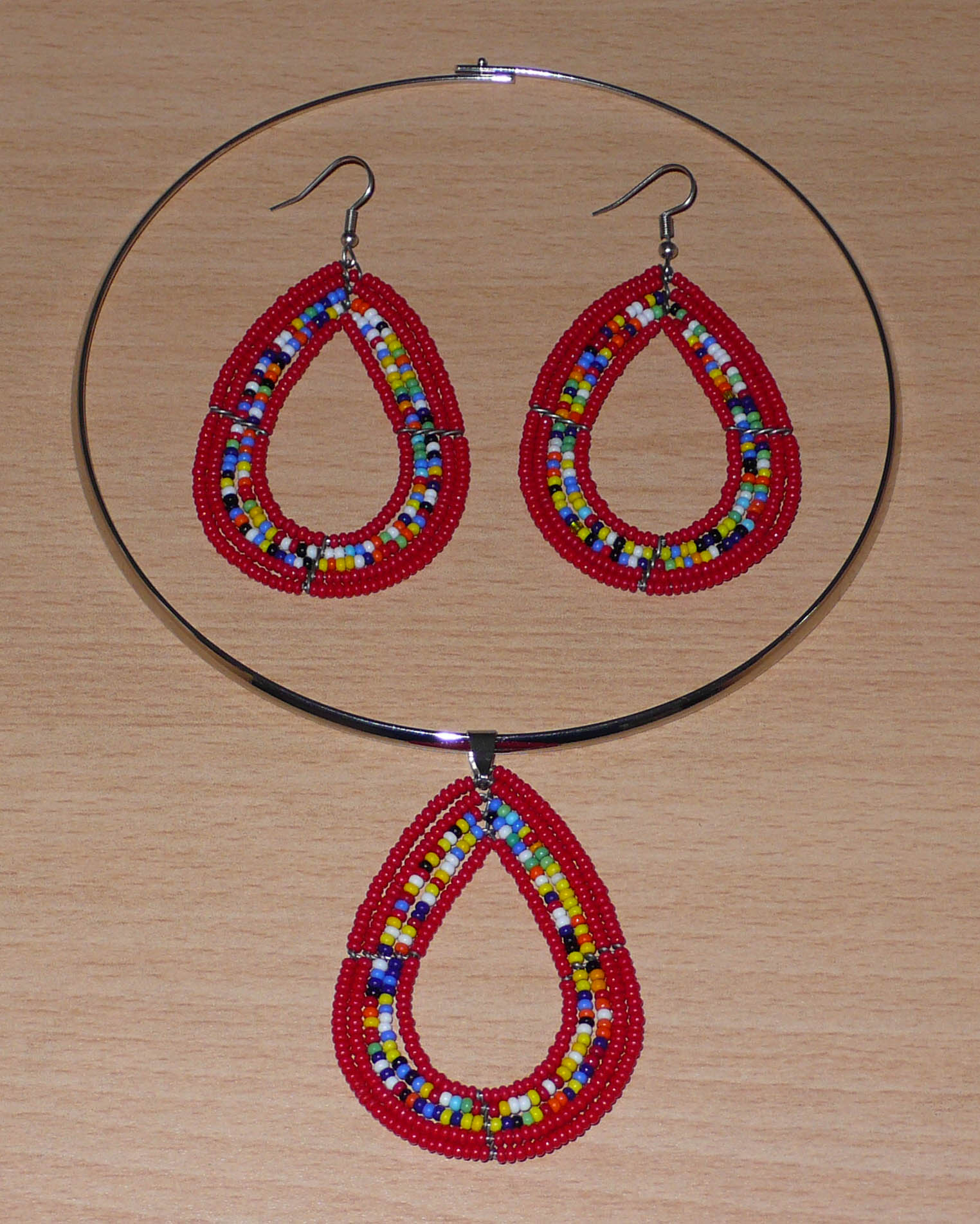 Parure de bijoux ethniques composée d'un collier ras-de-cou orné d'un pendentif en forme de goutte fait de perles de rocaille rouges et multicolores, et d'une paire de boucles d'oreilles assorties.