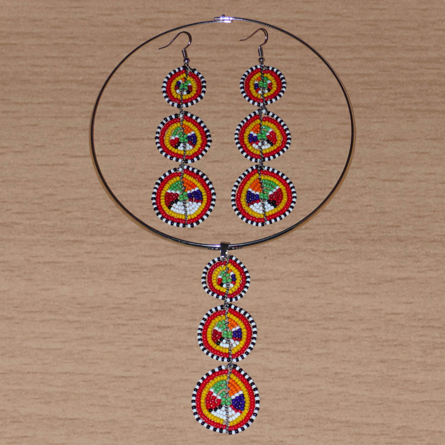 Le style ethnique afro chic des années 70 est à l'honneur avec cette parure de bijoux africains Massai aux accents exotiques ! Elle se compose d'un collier ras de cou agrémenté d'un long pendentif fait de perles de rocaille multicolores façonnées en cercles superposés, et d'une paire de boucles d'oreilles assorties.