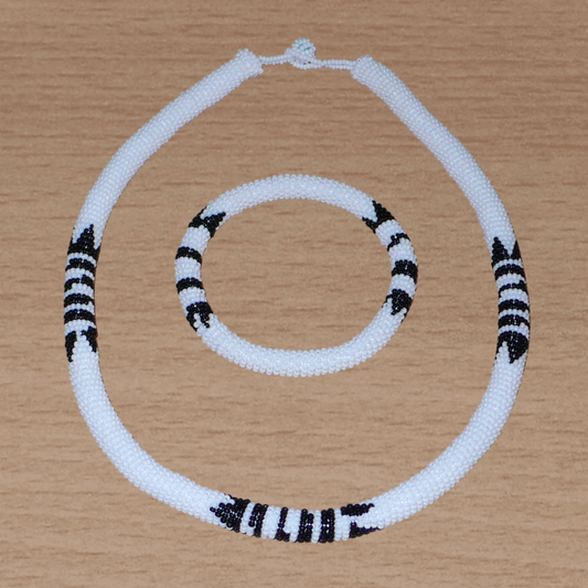 Parure de bijoux sud-africains traditionnels à motifs zoulous comprenant un collier et un bracelet composés de perles de rocaille blanches et noires.