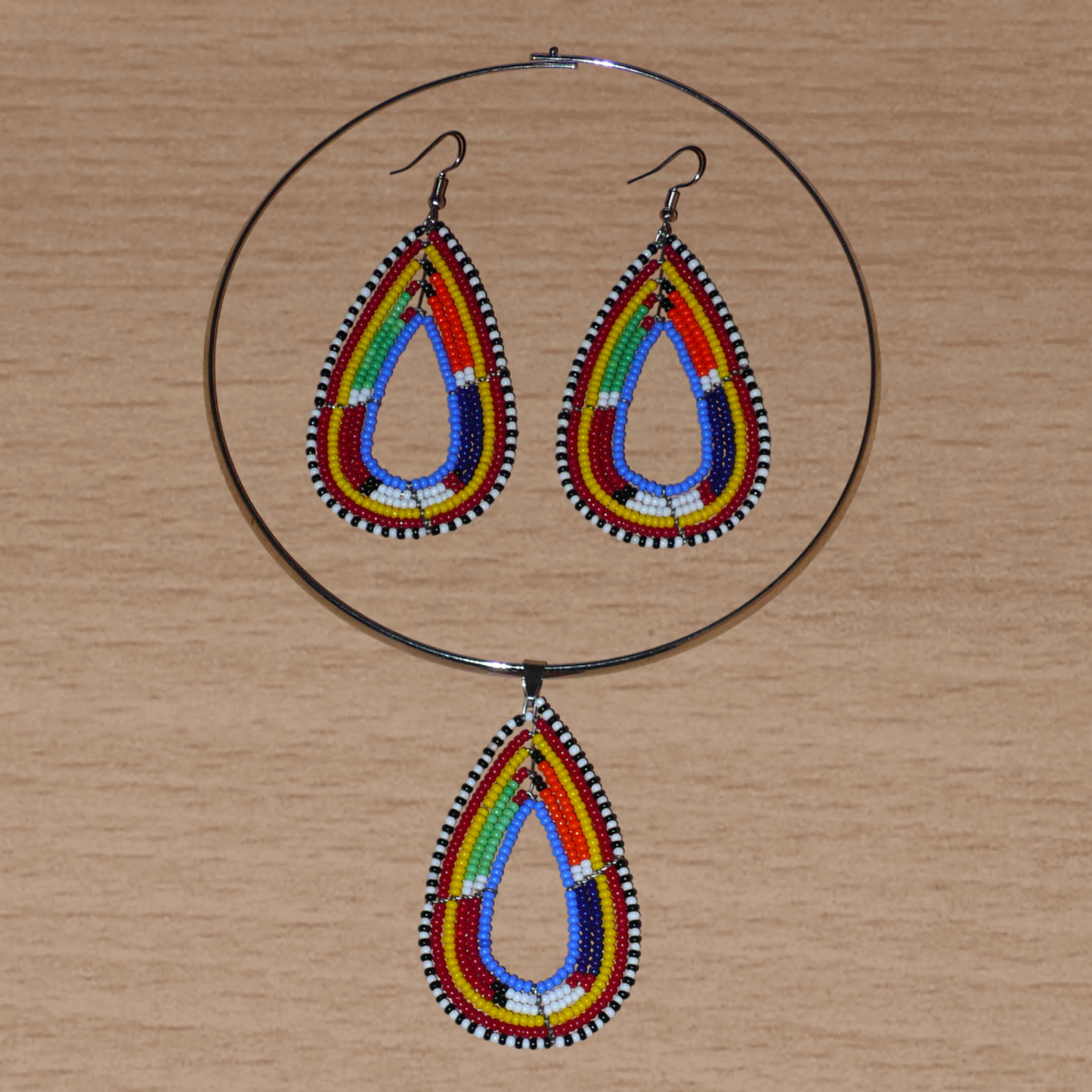 Apportez une touche ethnique chic à votre look avec cette parure contemporaine de bijoux africains alliant tradition Massai et modernité : elle se compose d'un collier ras de cou en laiton agrémenté d'un pendentif perlé en forme de goutte et d'une paire de boucles d'oreilles assorties.