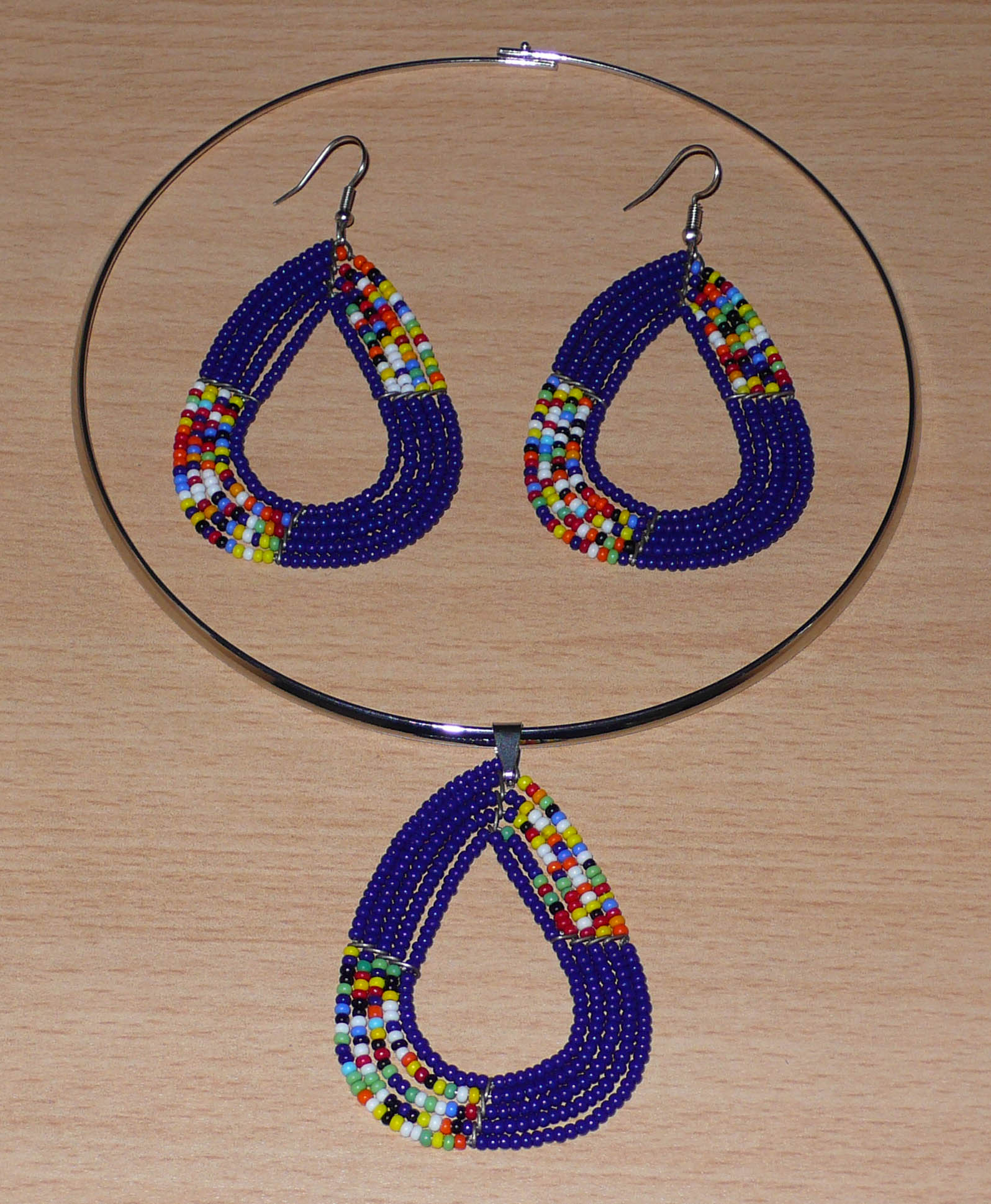 Parure de bijoux ethniques bleus et multicolores composée d'un collier ras de cou en laiton orné d'un pendentif fait de perles de rocaille, et d'une paire de boucles d'oreilles assorties.