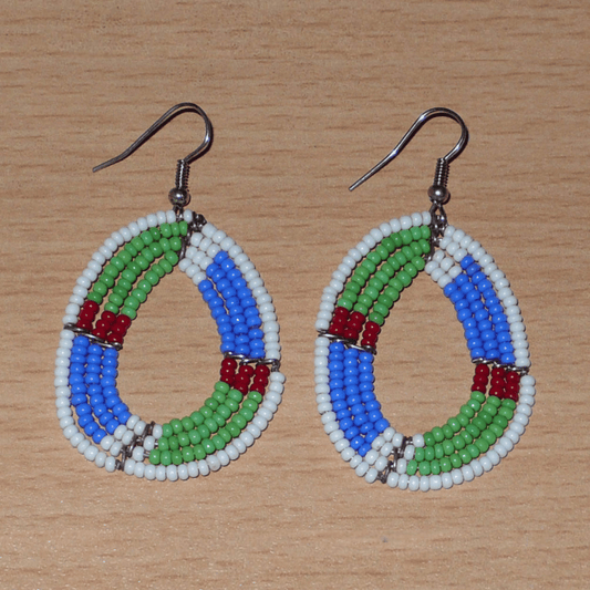 Boucles d'oreilles africaines Massai en forme de gouttes composées de perles de rocaille vertes, bleues, rouges et blanches. Elles mesurent 6 cm de long et 3,5 cm de large et se portent avec des crochets en acier inoxydable sur des oreilles percées.