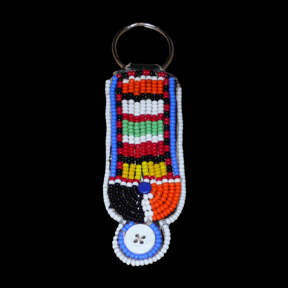 Porte-clés africain à motifs traditionnels Massai composé de perles de rocaille multicolores et de boutons brodés sur un morceau de cuir. Ce porte-clés, brodé sur les deux faces, mesure 10,5 cm de long et 3 cm de large.