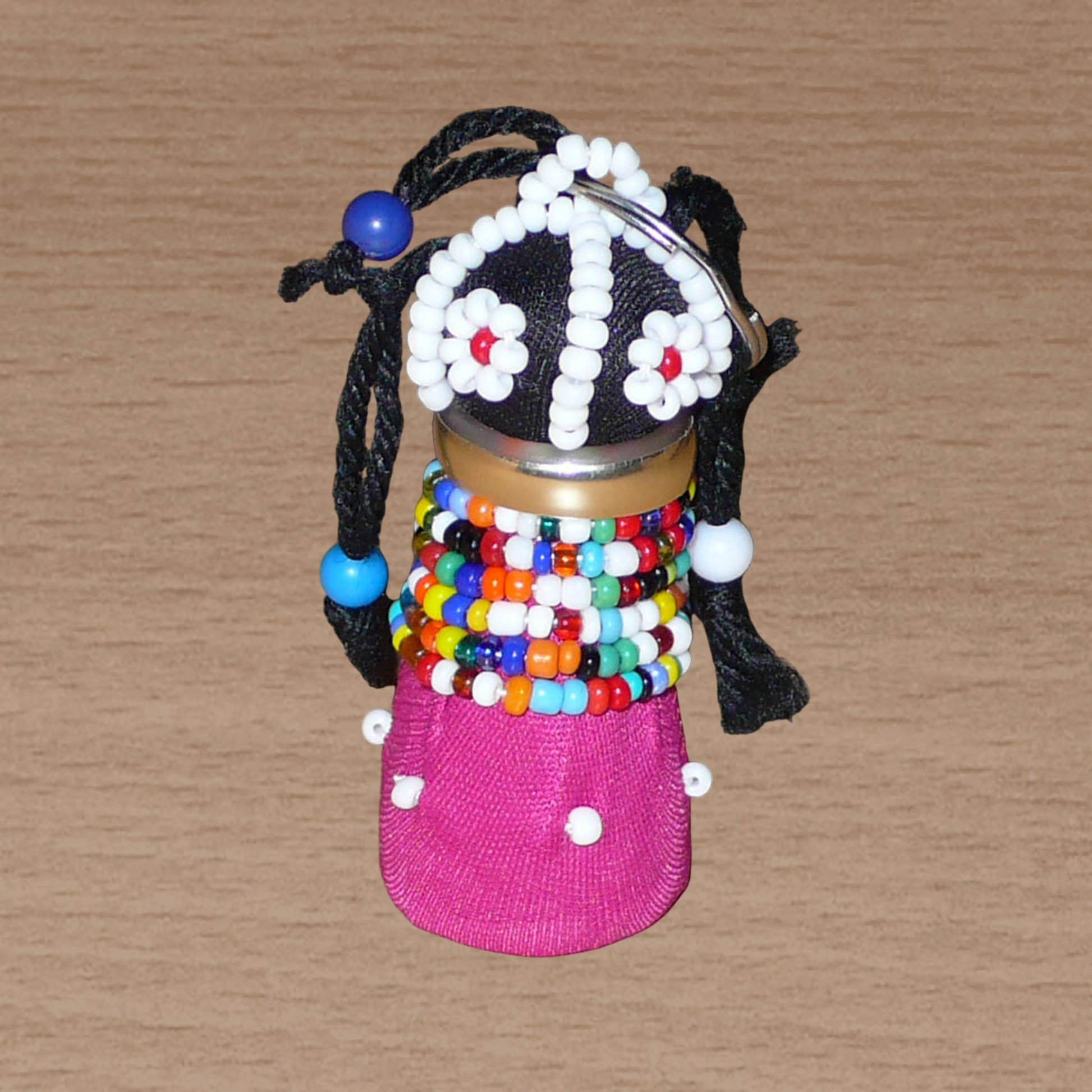 Porte-clés africain en forme de poupée Ndebele fabriqué avec du tissu en coton rose et noir, de la laine, de l'acier, et des perles de rocaille et de plastique multicolores.