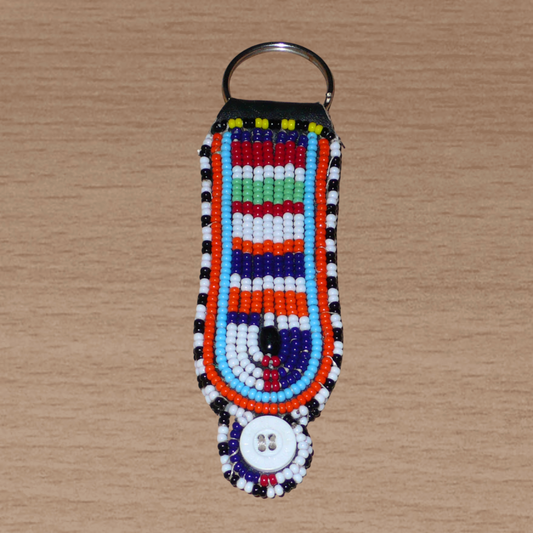 Porte-clés africain Massai composé de perles de rocaille multicolores et de boutons brodés sur un morceau de cuir. Ce porte-clés, brodé sur les deux faces, mesure 10,5 cm de long et 3 cm de large.
