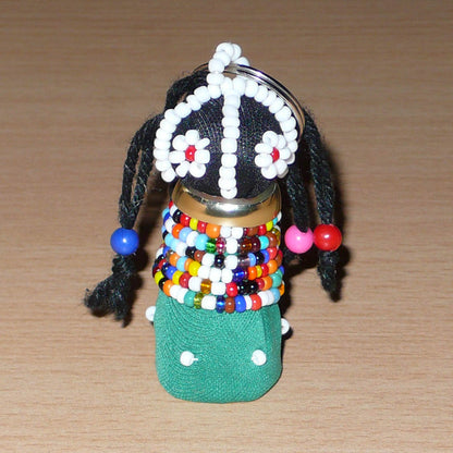 Porte-clés sud-africain en forme de poupée traditionnelle Ndebele composé de tissu en coton vert pour sa robe, de coton noir pour son visage, de laine pour ses cheveux, de laiton pour son collier et de perles de rocaille et en plastique blanches et multicolores