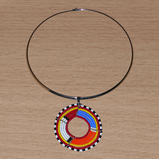 Bijou ethnique Massai composé d'un collier ras de cou rehaussé d'un pendentif rond composé de perles de rocaille principalement bleues, rouges, blanches et orange.
