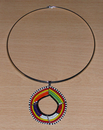 Bijou africain composé d'un collier ras de cou en laiton orné d'un pendentif aux motifs et couleurs Massai en perles de rocaille.