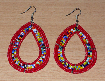 Boucles d'oreilles ethniques multi-rangs en forme de gouttes faites de perles de rocaille rouges et multicolores. Elles mesurent 8 cm de long et 4,5 cm de large, et se portent sur des oreilles percées.