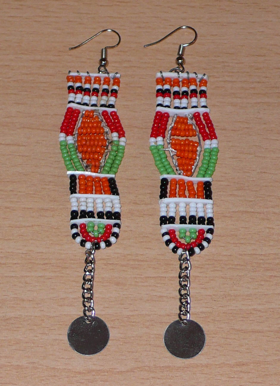 Longues boucles d'oreilles africaines Massai faites de perles de rocaille et prolongées d'une chaînette ornée d'un disque de métal. Ces boucles d'oreilles afro chic mesurent 12 cm de long et 2,5 cm de large.