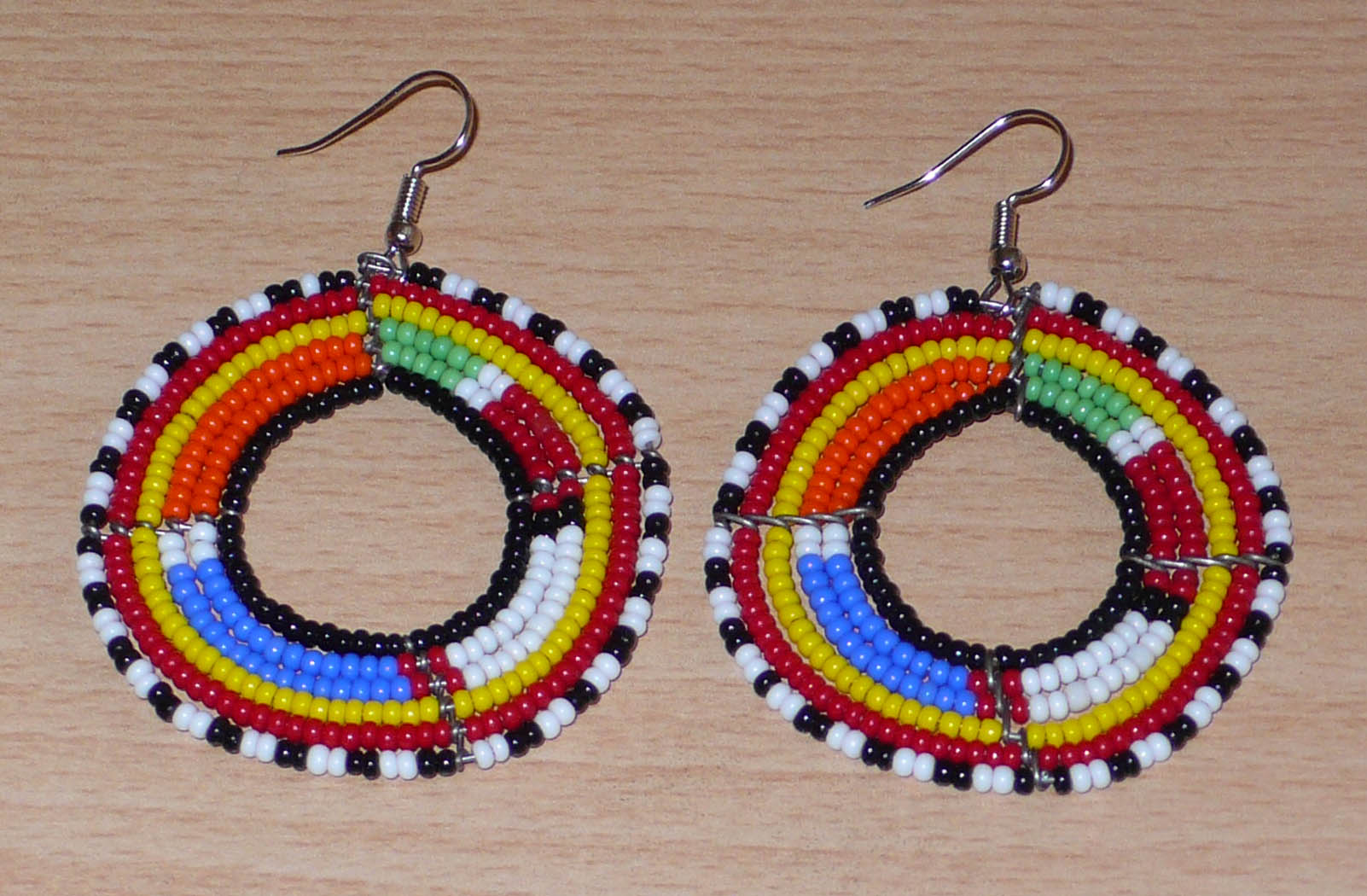 Boucles d'oreilles africaines traditionnelles Massai en perles de rocaille multicolores montées en forme de cercles. Elles mesurent  7 cm de long sur 5 cm de large.