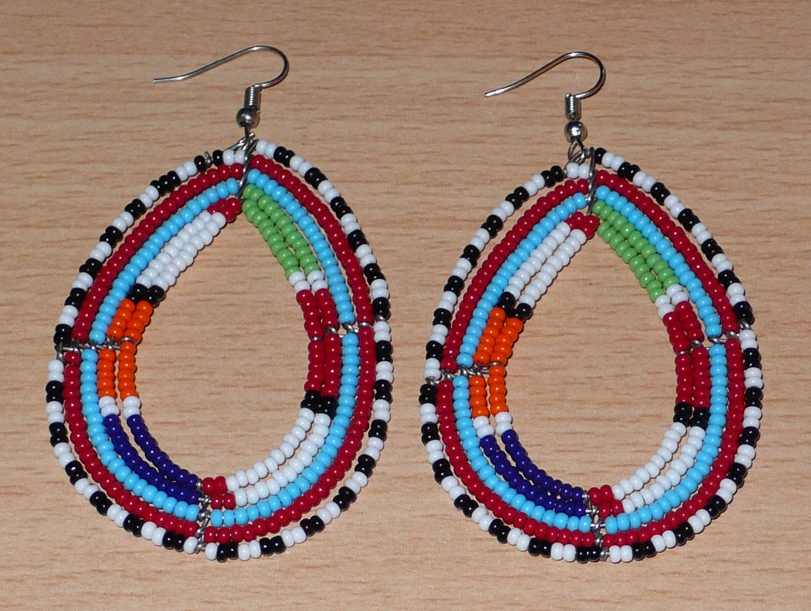 Boucles d'oreilles africaines à motifs ethniques Massai faites de perles de rocaille multicolores montées en forme de gouttes. Elles mesurent 8,5 cm de long et 4,5 cm de large et se portent sur des oreilles percées.