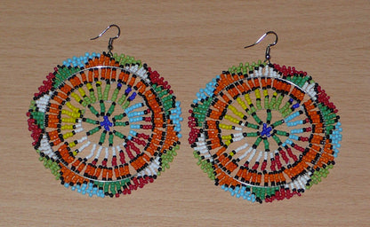 Boucles d'oreilles sud-africaines rondes surdimensionnées à motifs zoulous composées de perles de rocaille multicolores. Longues et larges, elles mesurent 10 cm de long et 8,5 cm de large, et se portent sur des oreilles percées.