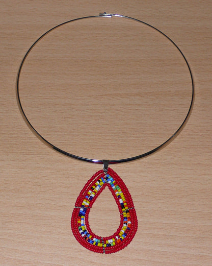 Collier ethnique de style afro bohème composé d'un ras de cou en laiton orné d'un pendentif en forme de goutte fait de perles de rocaille rouges et multicolores. Il mesure 20 cm de long, la circonférence du ras de cou en laiton est de 42,5 cm et son diamètre de 13,5 cm ; le pendentif perlé mesure 7 cm de long et 4,5 cm de large.