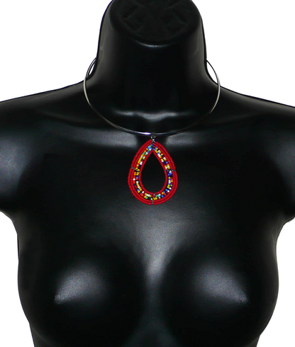 Collier ethnique de style afro bohème composé d'un ras de cou en laiton orné d'un pendentif en forme de goutte fait de perles de rocaille rouges et multicolores. Il mesure 20 cm de long, la circonférence du ras de cou en laiton est de 42,5 cm et son diamètre de 13,5 cm ; le pendentif perlé mesure 7 cm de long et 4,5 cm de large.