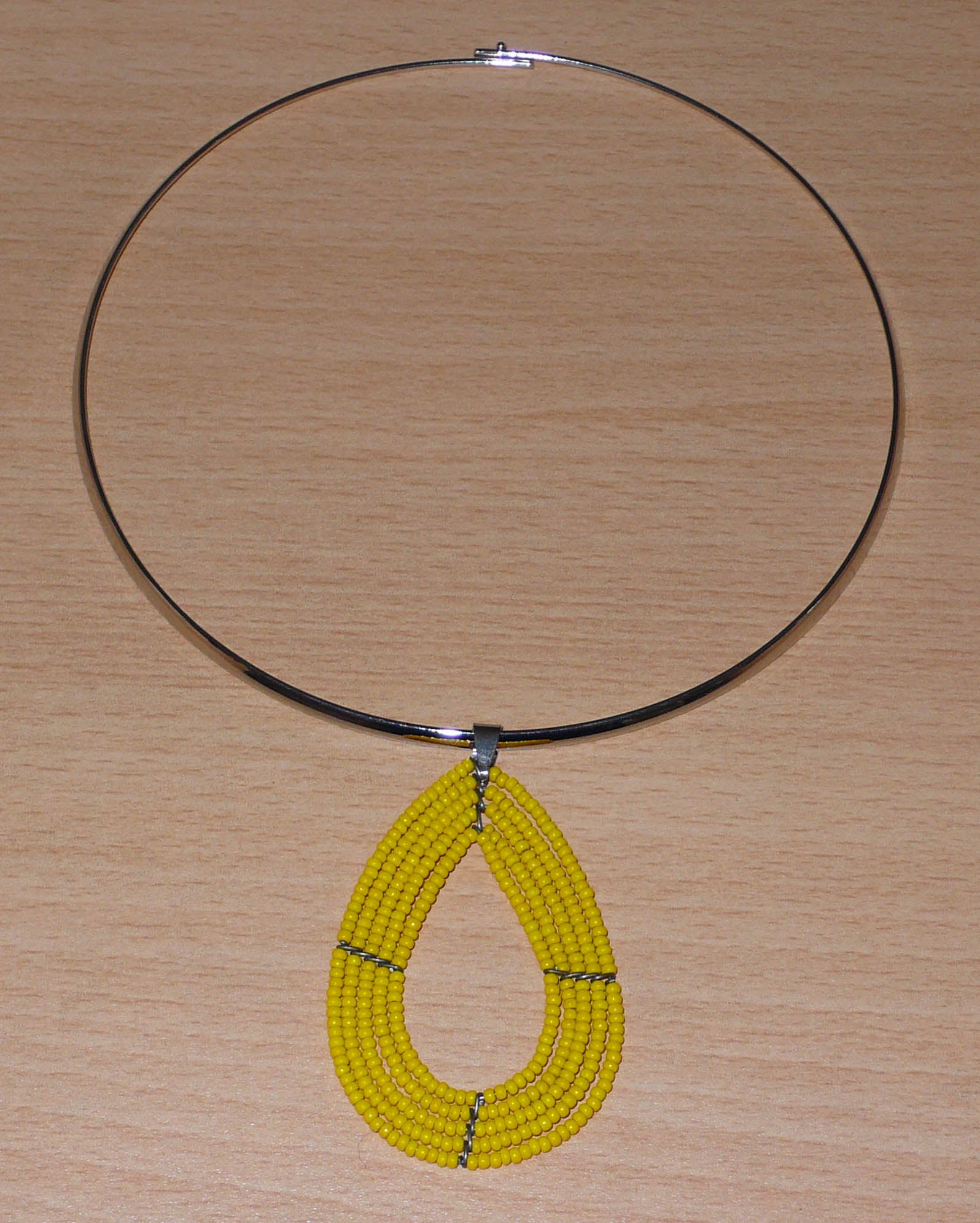 Collier jaune composé d'un ras de cou en laiton orné d'un pendentif multi-rangs fait de perles de rocaille montées en forme de goutte.