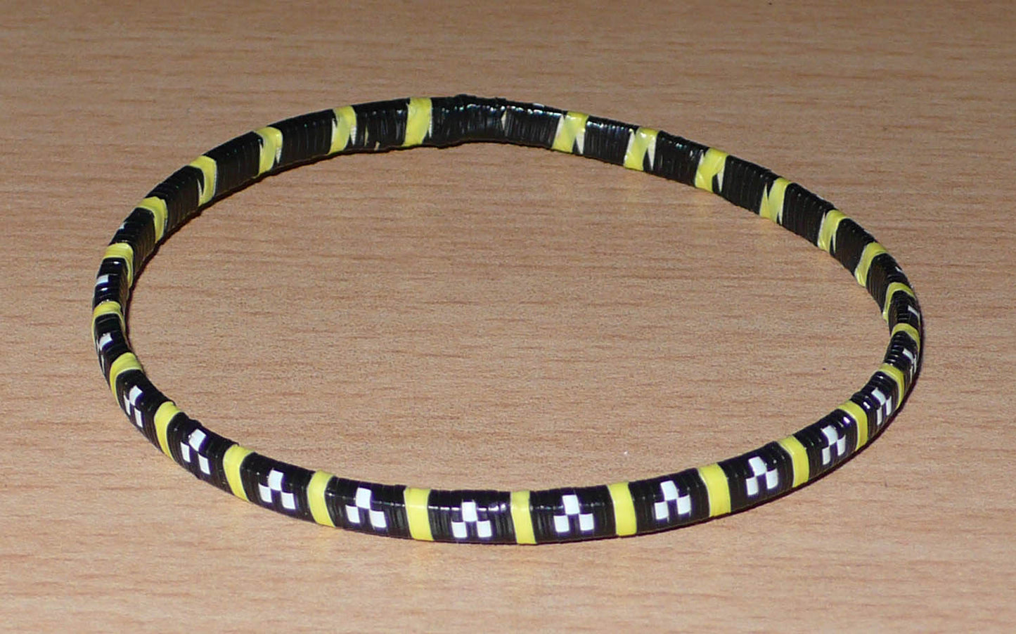 Empilez-les sur vos poignets ! Ensemble de 12 bracelets africains tricolores fabriqués au Mali à partir de fines bandes de plastique recyclé noir, jaune et blanc.  Ces bracelets, très fins, ont une circonférence de 20,5 cm, un diamètre de 6,5 cm et une épaisseur de 0,5 cm.  Ils peuvent être portés par une femme ou par un homme.