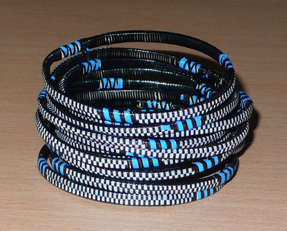Lot de 12 bracelets africains tricolores fabriqués dans une démarche éco-responsable à partir de plastique recyclé noir, bleu et blanc.  Ces bracelets ont une circonférence de 19,5 cm, un diamètre de 6,3 cm et une épaisseur de 0,5 cm. Timeless Fineries
